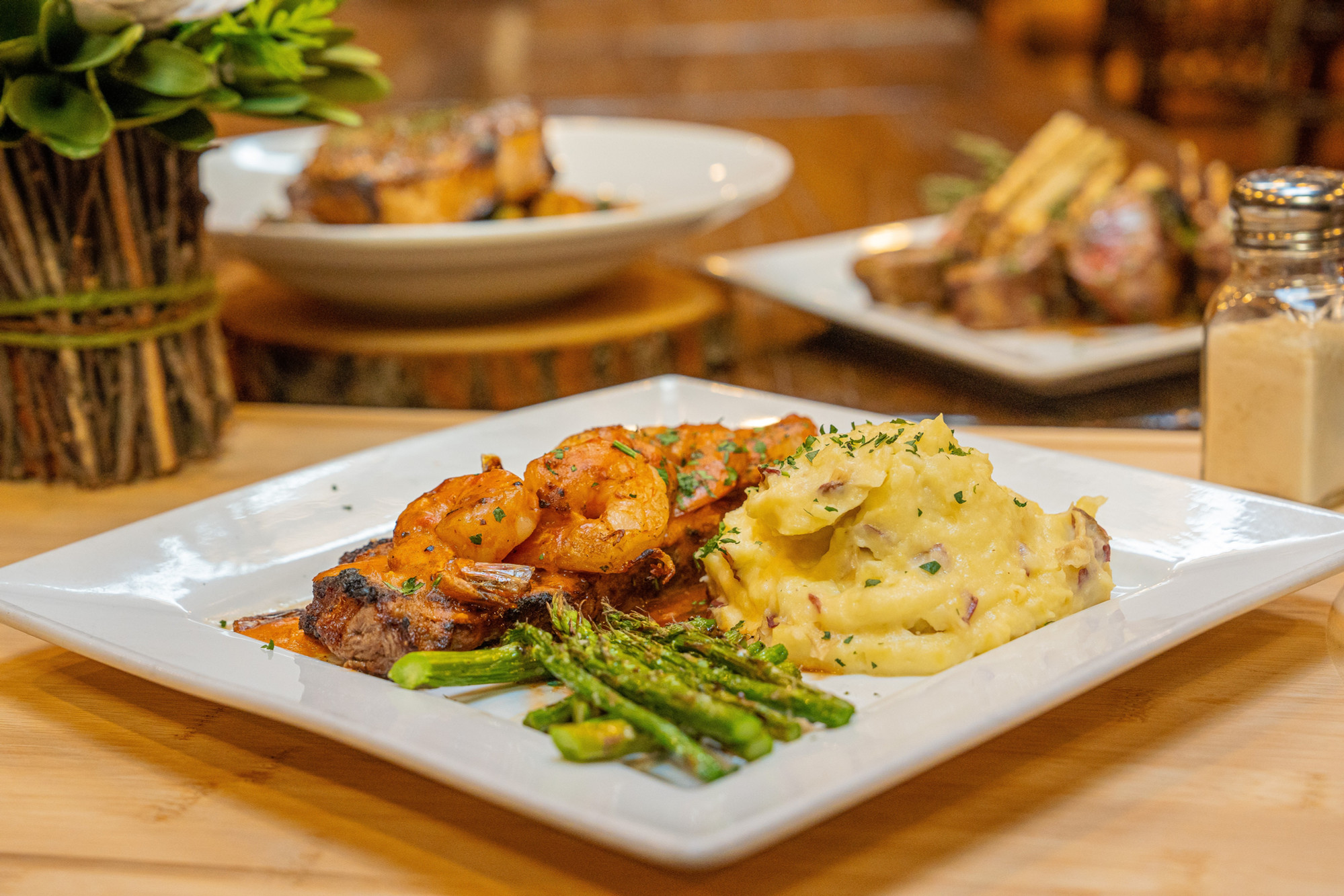Steak topped with grilled shrimp, mashed potatoes and asparagus